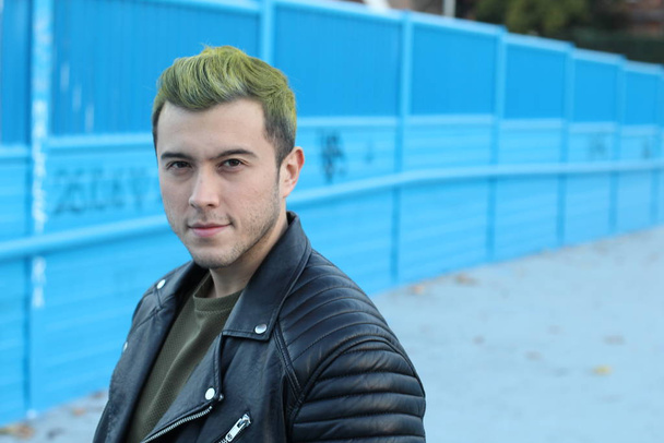 közeli felvétel jóképű fiatalember színes hajjal, stílusos ruhákkal az utcán - Fotó, kép
