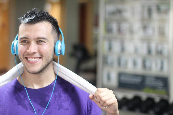 Hombre étnico motivado que escucha música en el gimnasio - Foto, imagen
