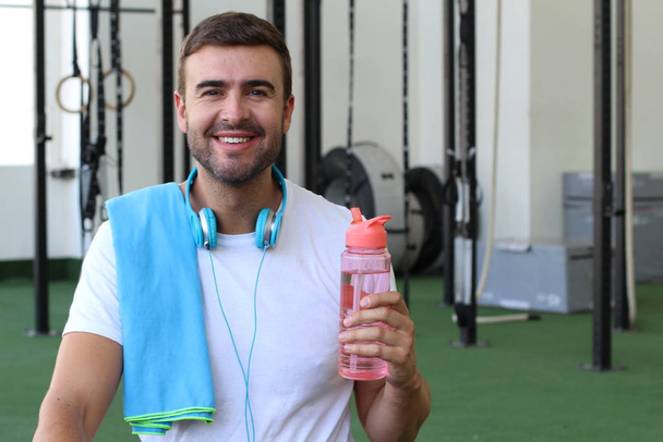 Homem usando uma garrafa de água plástica reutilizável no ginásio
 - Foto, Imagem