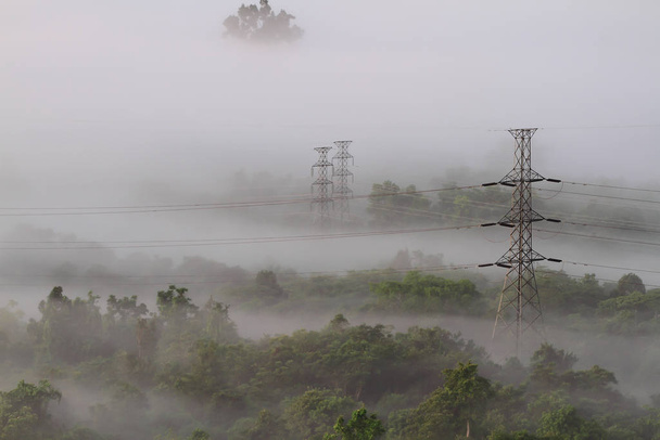 Elektrické elektrické vedení a pylony vznikající z mlhy - Fotografie, Obrázek