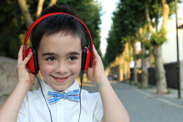 Крупним планом портрет стильного хлопчика в червоних навушниках, що стоїть на відкритому повітрі
  - Фото, зображення