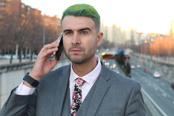Elegante knappe man met groen haar aan de telefoon in de stad - Foto, afbeelding