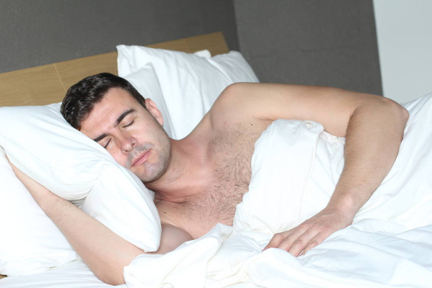 Ο εθνοτικός άντρας κοιμήθηκε βαθιά στο άνετο κρεβάτι. - Φωτογραφία, εικόνα