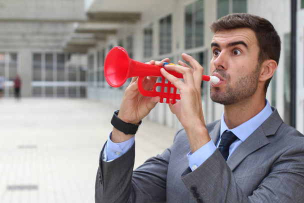 Ruidoso hombre de negocios tocando una trompeta de plástico
 - Foto, imagen