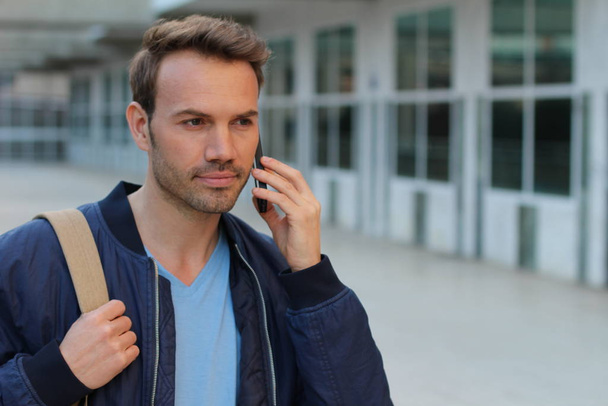 close-up portrait of handsome young man talking by phone on street - Photo, image
