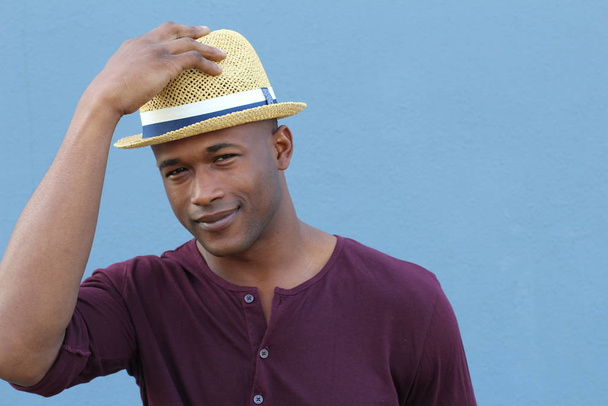 close-up portrait of handsome young african american man in hat in front of blue wall - Photo, Image