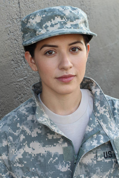 Ritratto di bella ragazza che indossa giacca e cappello verde stile militare, sfondo grigio muro
  - Foto, immagini