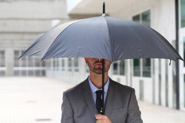 Επιχειρηματίας κρύβεται κάτω από μια ομπρέλα στο χώρο του γραφείου - Φωτογραφία, εικόνα