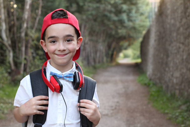 Closeup portrait of stylish child boy in red headphones standing outdoors  - Photo, Image