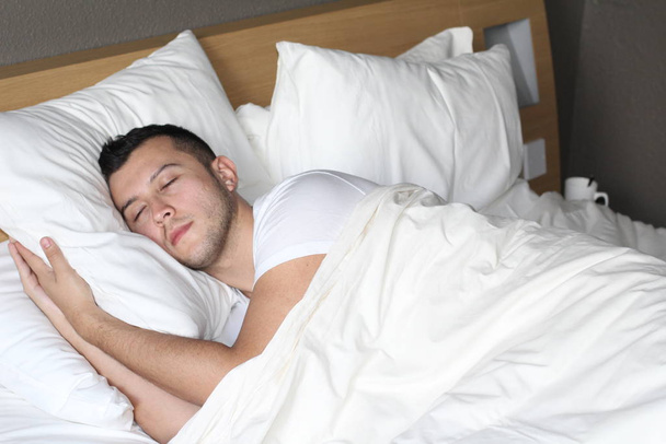 Homem étnico profundamente dormiu em cama confortável
 - Foto, Imagem