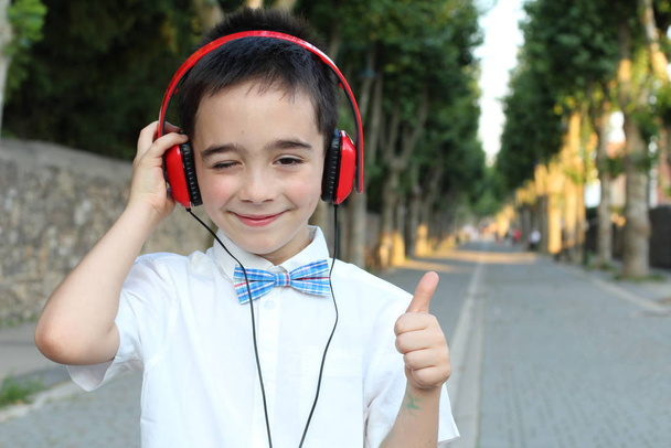 Closeup portrait of stylish child boy in red headphones standing outdoors  - Valokuva, kuva
