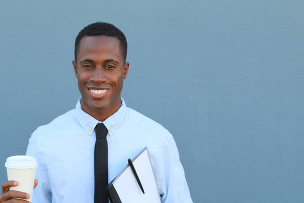 ritratto ravvicinato di un bel giovane uomo d'affari afroamericano in camicia con cravatta e cartellina e tazza di caffè davanti alla parete grigia
 - Foto, immagini