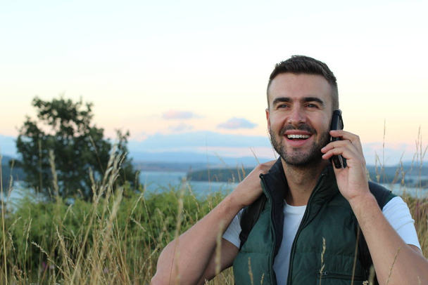 close-up portrait of handsome young man talking by phone on nature - Fotoğraf, Görsel