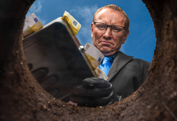 Un homme d'affaires enterre son argent dans un trou de terre
 - Photo, image