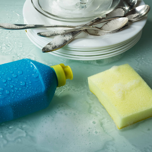 Washing dishes with special tool, yellow sponge and plates in the foam - Fotografie, Obrázek