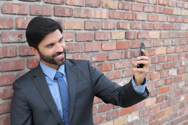 Mladý podnikatel brát selfie s jeho smartphone na cihlové zdi pozadí  - Fotografie, Obrázek