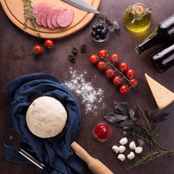 Top view. Ingredients for making flavorful pepperoni pizza on dark background - Foto, immagini