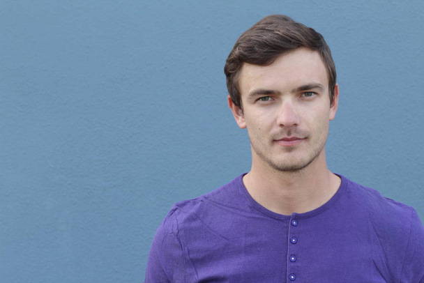 zblízka portrét pohledného mladého muže v purpurové košili před modrou stěnou - Fotografie, Obrázek