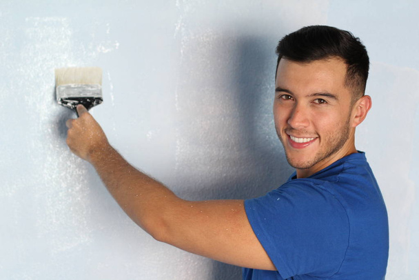 Χαρούμενο αρσενικό, έτοιμο να βάψει έναν τοίχο στο σπίτι του. - Φωτογραφία, εικόνα