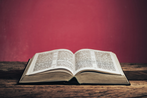 Open bible on a old oak wooden table. Beautiful green wall background. - Photo, Image