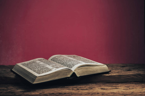 Ανοίξτε τη Βίβλο σε ένα παλιό ξύλινο τραπέζι βελανιδιάς. Όμορφο πράσινο φόντο τοίχο. - Φωτογραφία, εικόνα