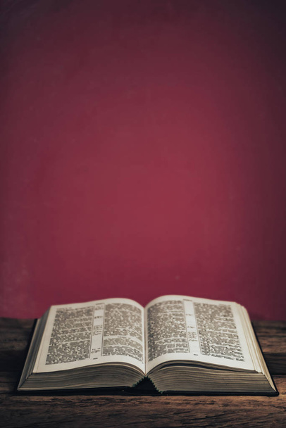 Otwórz Biblię na starym dębowym drewnianym stole. Piękne zielone tło ściany. - Zdjęcie, obraz