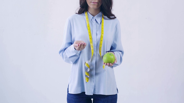 обрізаний вид жінки, що вибирає між вітамінами та яблуком, ізольований на білому
 - Кадри, відео