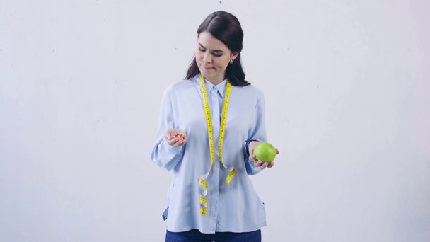 mulher atraente comparando vitaminas e maçã isolada em branco
 - Filmagem, Vídeo