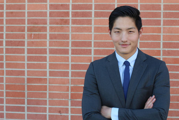 Nahaufnahme Porträt eines hübschen jungen asiatischen Geschäftsmannes vor einer Ziegelwand - Foto, Bild