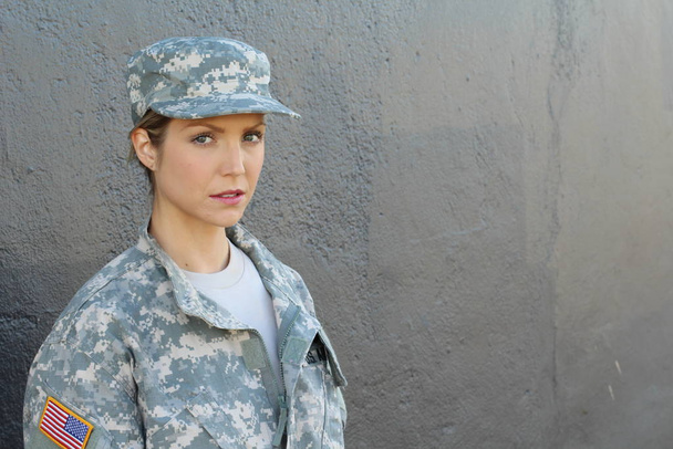 Gorgeous young woman in a Military costume on gray background - Foto, Imagen