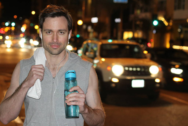 крупним планом портрет красивого молодого чоловіка зі спортивною пляшкою та рушником на вечірній вулиці
 - Фото, зображення