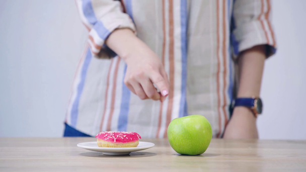 vista recortada de la mujer elegir entre manzana y donut
 - Metraje, vídeo