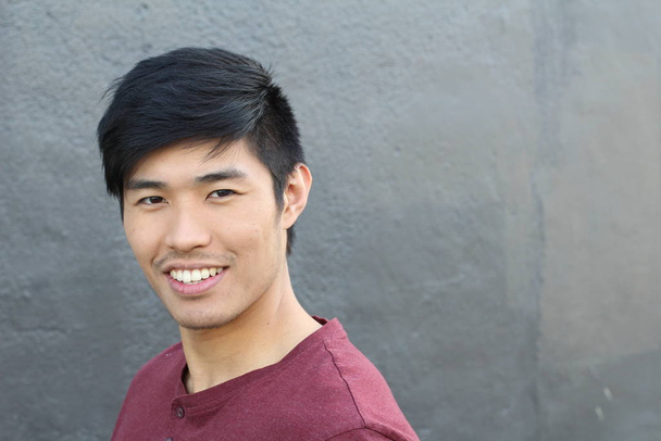 close-up portrait of handsome young asian man in front of grey wall - 写真・画像