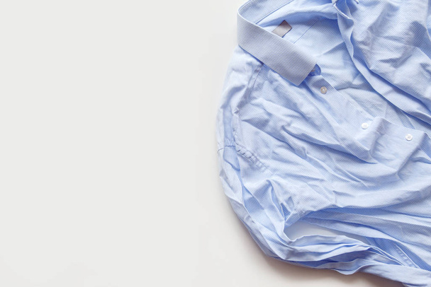 Blue cotton wrinkled and rumpled shirt on white. Washed shirt after tumble dryer - 写真・画像