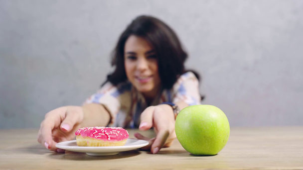 selective focus of apple and doughnut near confused girl - Filmagem, Vídeo