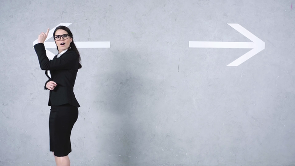Geschäftsfrau mit Brille geht neben Pfeilen auf grau - Filmmaterial, Video
