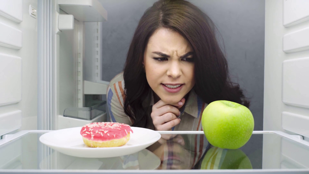 mooi meisje nemen donut uit koelkast - Video