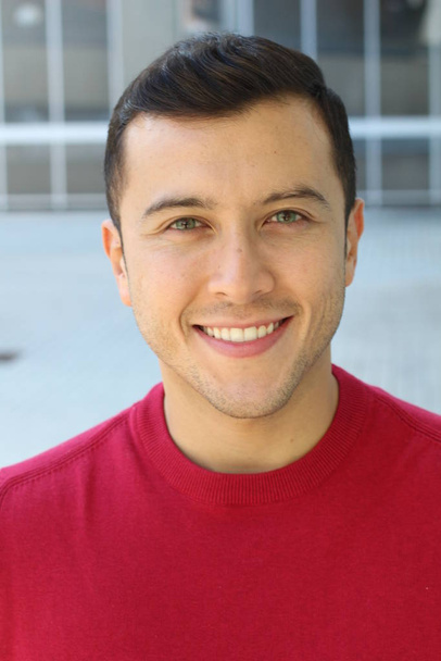 közeli kép egy jóképű fiatalemberről piros pulóverben az utcán - Fotó, kép