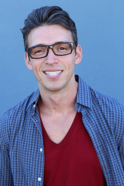 közeli kép egy jóképű fiatalemberről kockás ingben a kék fal előtt. - Fotó, kép