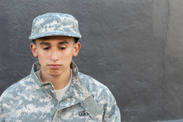 γκρο πλαν πορτρέτο του όμορφου νεαρού στρατιώτη μπροστά από γκρίζο τσιμεντένιο τοίχο - Φωτογραφία, εικόνα