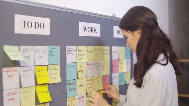 attractive scrum master putting sticky note with ui lettering on board  - Footage, Video