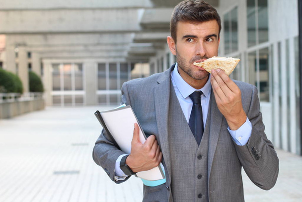 Uomo d'affari che cammina e mangia allo stesso tempo
 - Foto, immagini