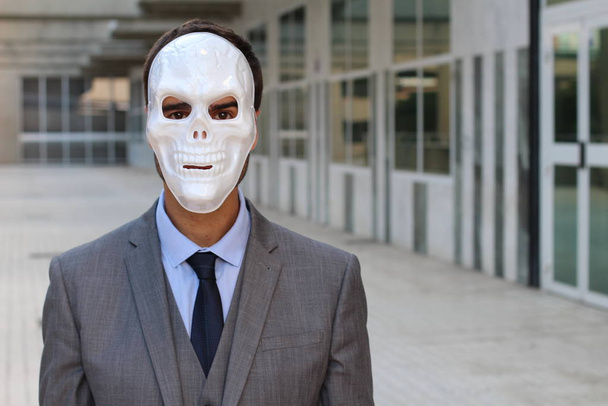 Nahaufnahme Porträt eines hübschen jungen Geschäftsmannes mit Halloween-Totenkopf-Maske auf der Straße - Foto, Bild