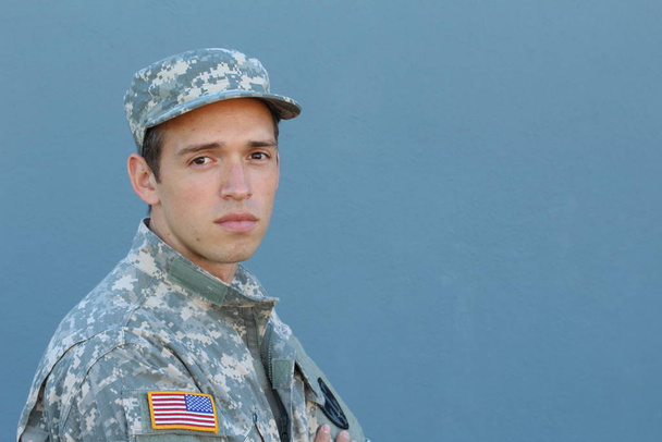 close-up portrait of handsome young soldier in uniform and cap in front of blue wall - 写真・画像