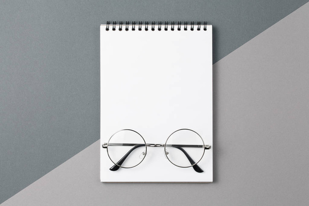 Notizbuch mit Brille auf grauem Hintergrund von oben. - Foto, Bild