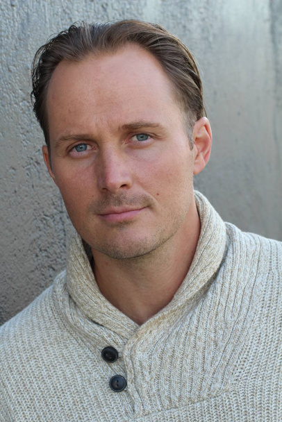 close-up portret van knappe jongeman in trui voor grijze muur - Foto, afbeelding