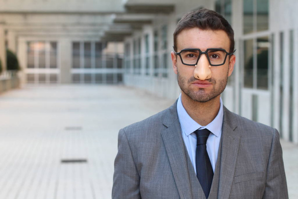 close-up shot of handsome young businessman in grey suit with nose mask and eyeglasses on street - Foto, Bild