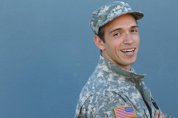 制服を着たハンサムな若い兵士のクローズアップ肖像と青い壁の前の帽子 - 写真・画像