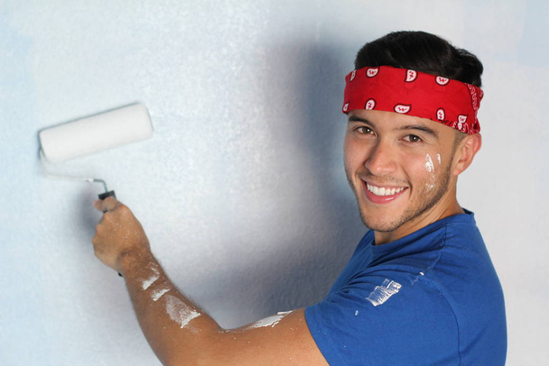Joyful ethnic male about to paint a wall in his home - 写真・画像