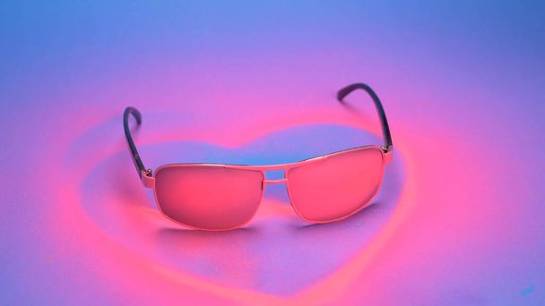 aurinkolasit on maalattu vaaleanpunaiseksi spraymaalilla sinisellä taustalla
 - Valokuva, kuva